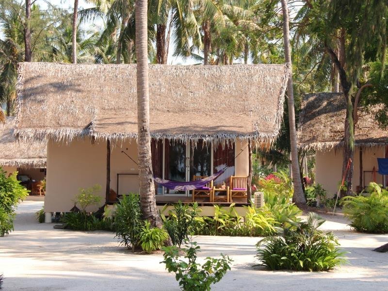 Thatched-roof bungalows and garden planting beneath palms at Angkana Hotel Bungalows