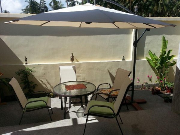 Outdoor table and chairs beneath a large umbrella at Khanom Garden Suite