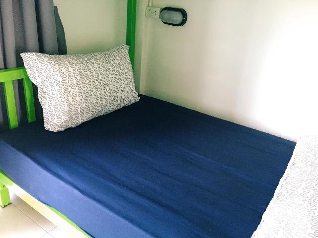 Single bed with blue bedding and a green frame at P Hostel Buriram