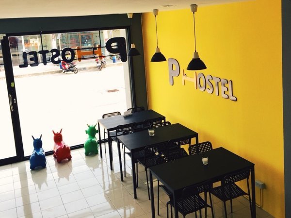 Yellow P Hostel common area with tables beside the glass entrance