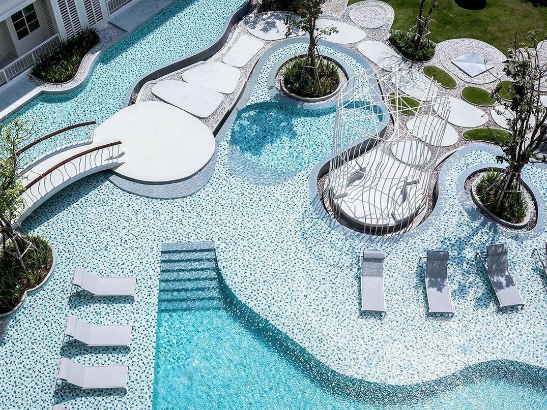 Curving shared swimming pool with submerged loungers at Summer Hua Hin