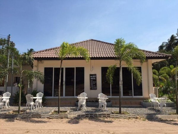 A low building with a tiled roof, front terrace and outdoor chairs at The Best Hostel
