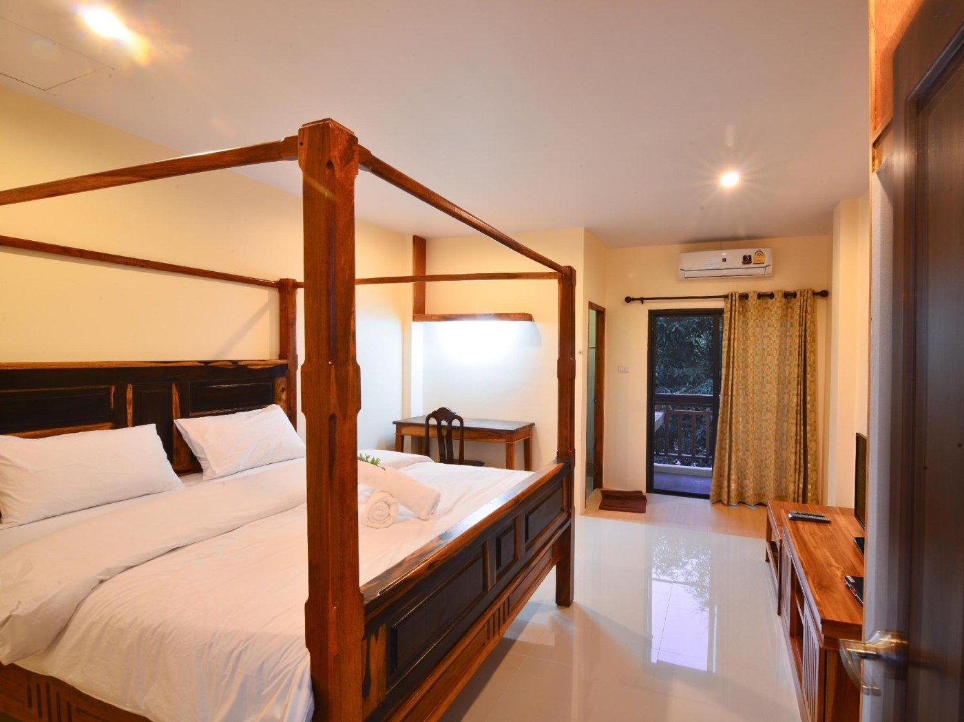 A four-poster bed, tiled floor and curtained doorway in a room at The Boon House
