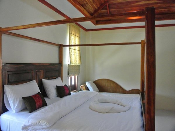 A wooden four-poster bed with white bedding and a sofa at The Boon House
