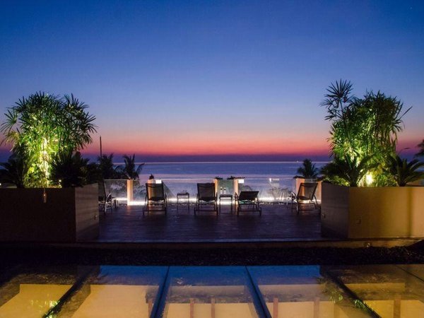 Poolside loungers and planting facing a coastal sunset at The Erawan Koh Chang