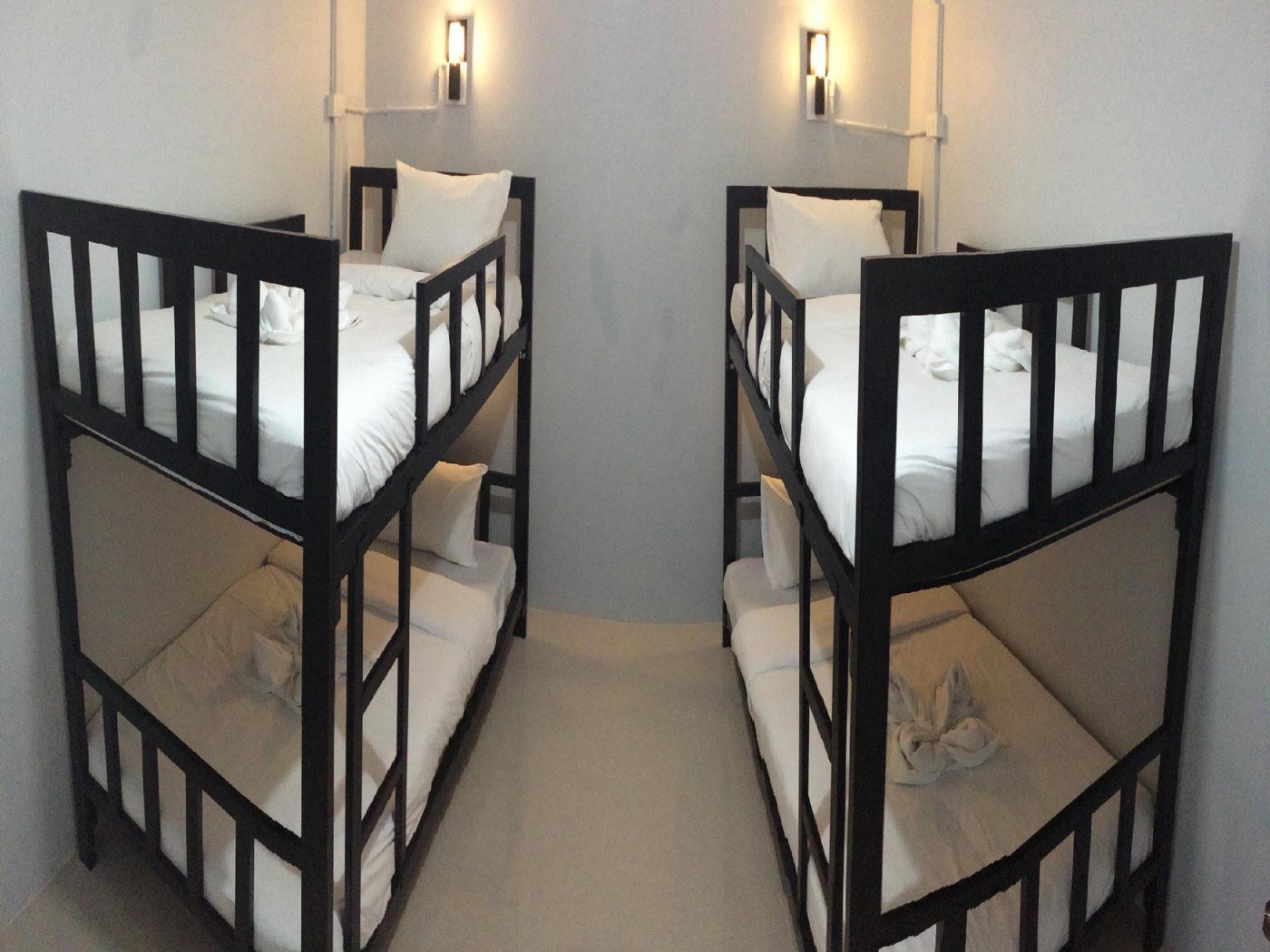 Two rows of black metal bunk beds with white bedding at The Metallic Hostel