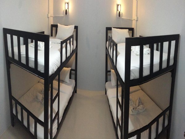 Two rows of black metal bunk beds with white bedding at The Metallic Hostel